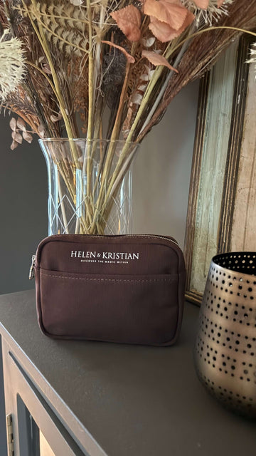 Stylish Nipsy Roasted Chestnut Clutch on table with decor.