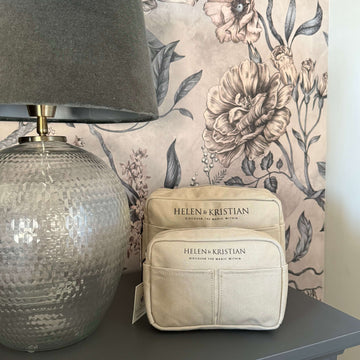 Nesty - Small Toiletry bag - Viking Haze displayed on a table beside a decorative lamp and floral wallpaper.