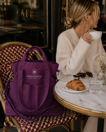 Organizer - Veske - Dusky Plum sitting on a cafe table with a woman enjoying coffee and a croissant.