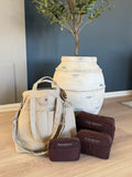 Veske - Organizer Viking Haze med tre smarte lommer foran en dekorativ potteplante.