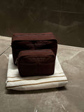 Nesty Roasted Chestnut petite trousse de toilette by Helen & Kristian on a towel, showcasing elegant and functional design.