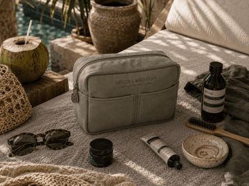 Nesty - Stor Toalettmappe - Deep Forest laying on a textured surface surrounded by beauty products and sunglasses.