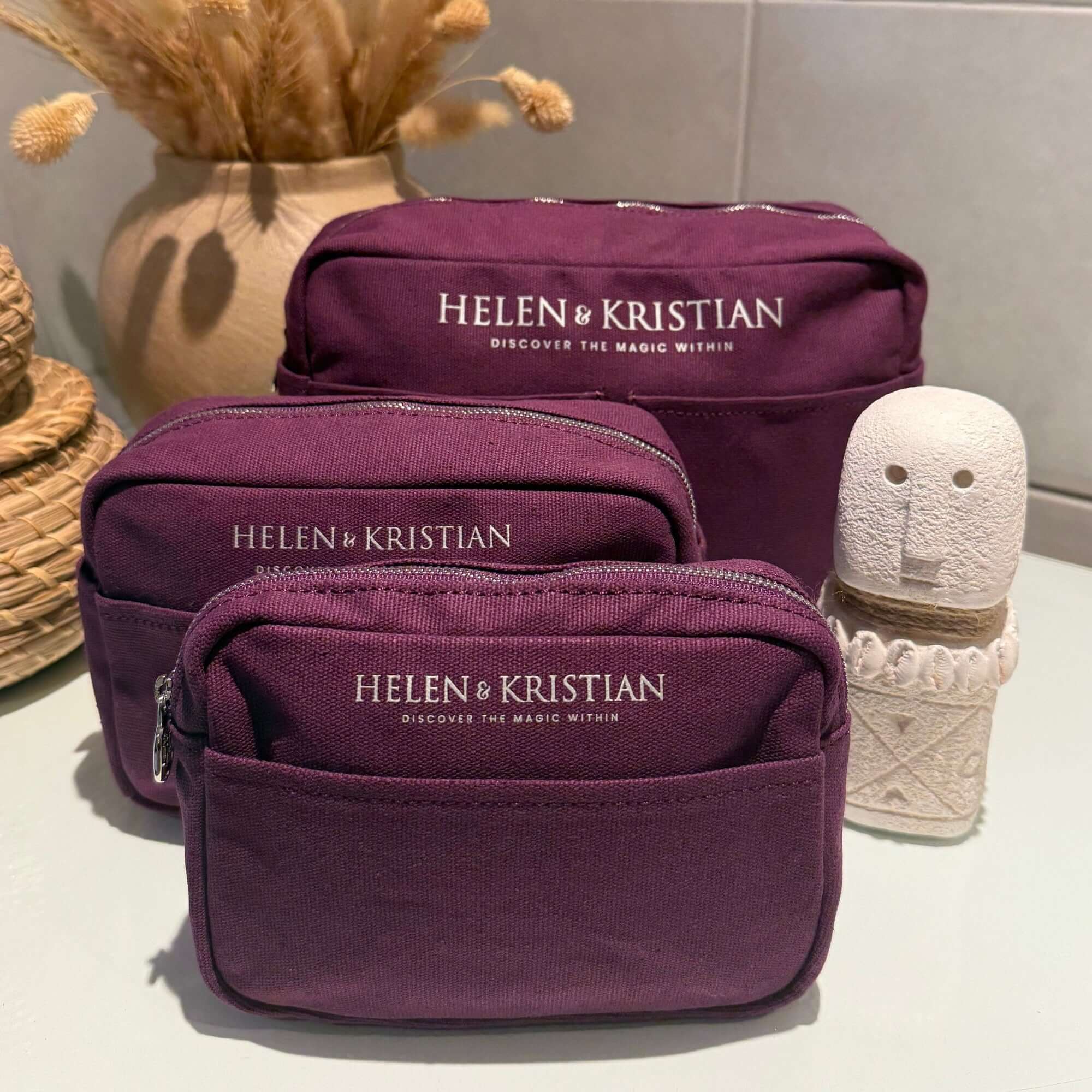Purple cosmetic bags with 'HELEN & KRISTIAN' branding on a neutral background