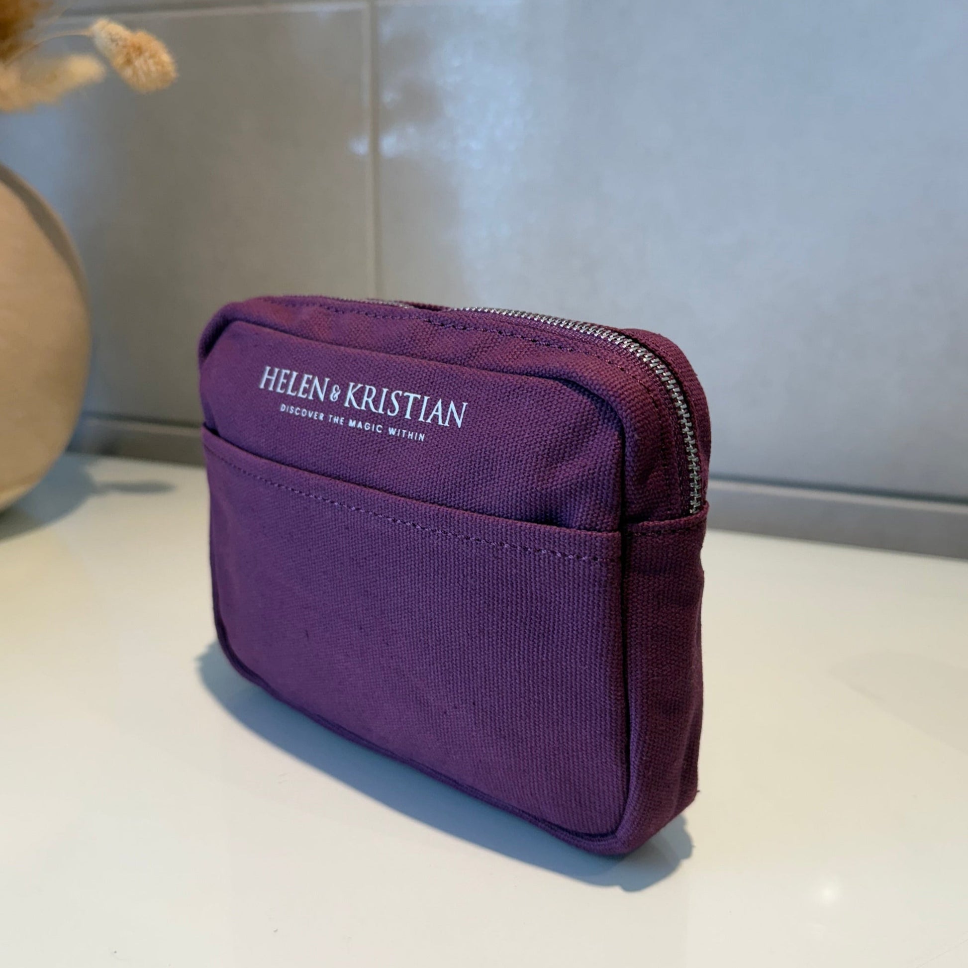 Purple cosmetic pouch with 'HELEN & KRISTIAN' branding .