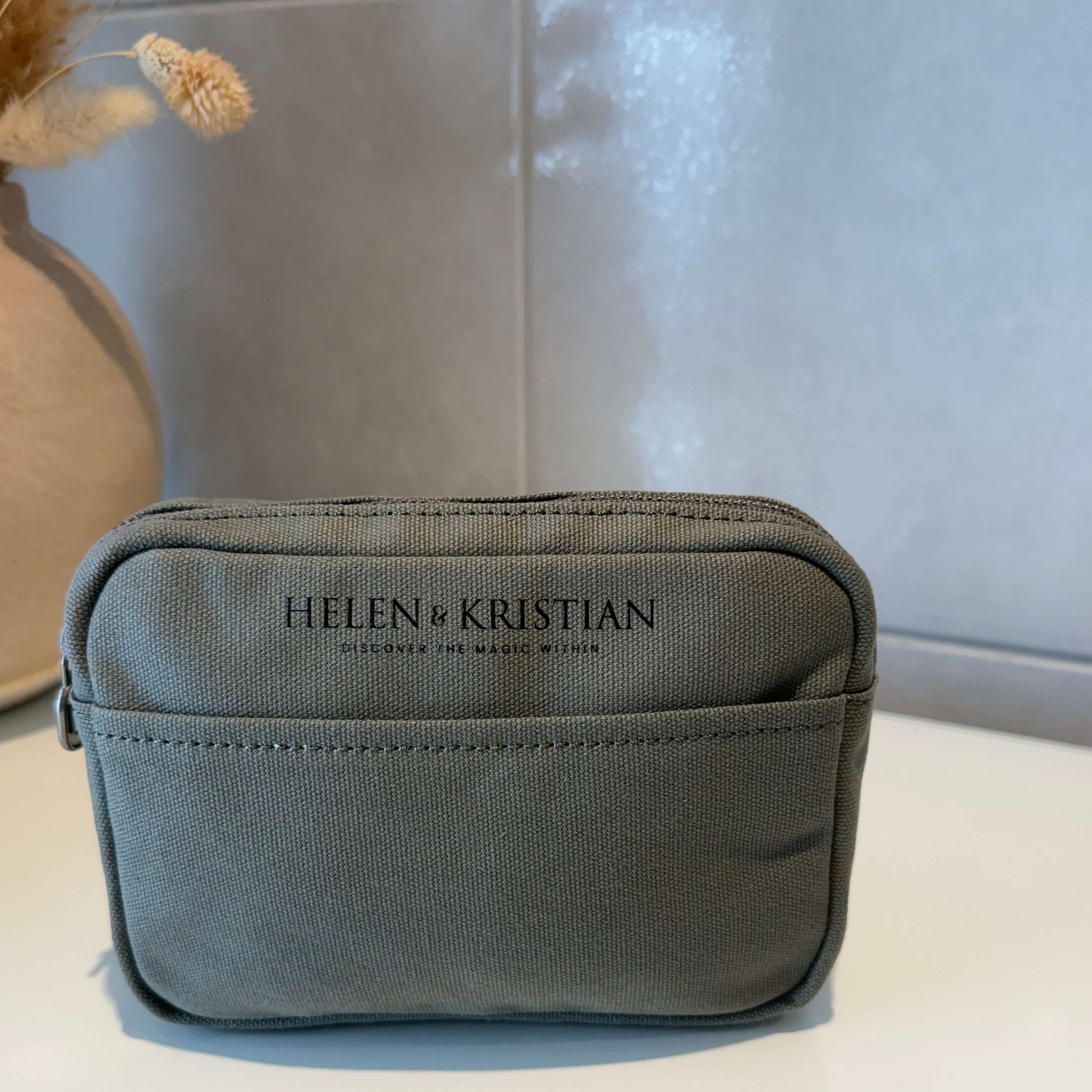 Green pouch with 'Helen Kristian' branding on a light background