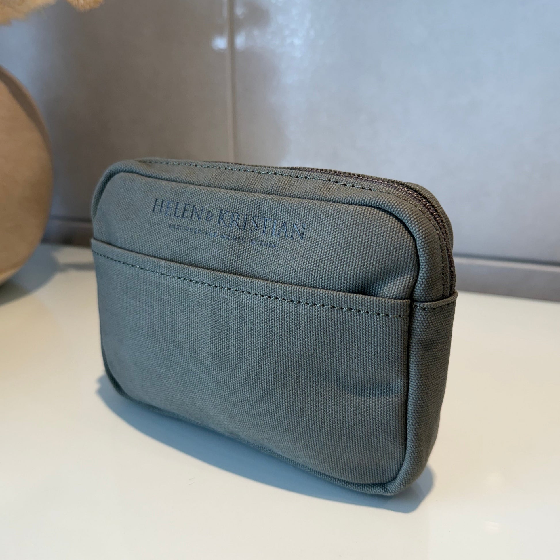Green cosmetic pouch on a desk with a tile background
